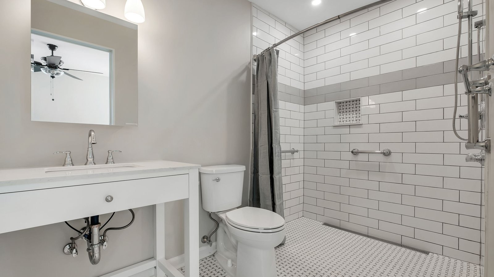 Curbless walk-in shower with white subway tile, integrated support rails, a handheld shower on a slide bar and a basketweave mosaic floor. Bathroom renovation by Pristine Renovations in Tallahassee, FL