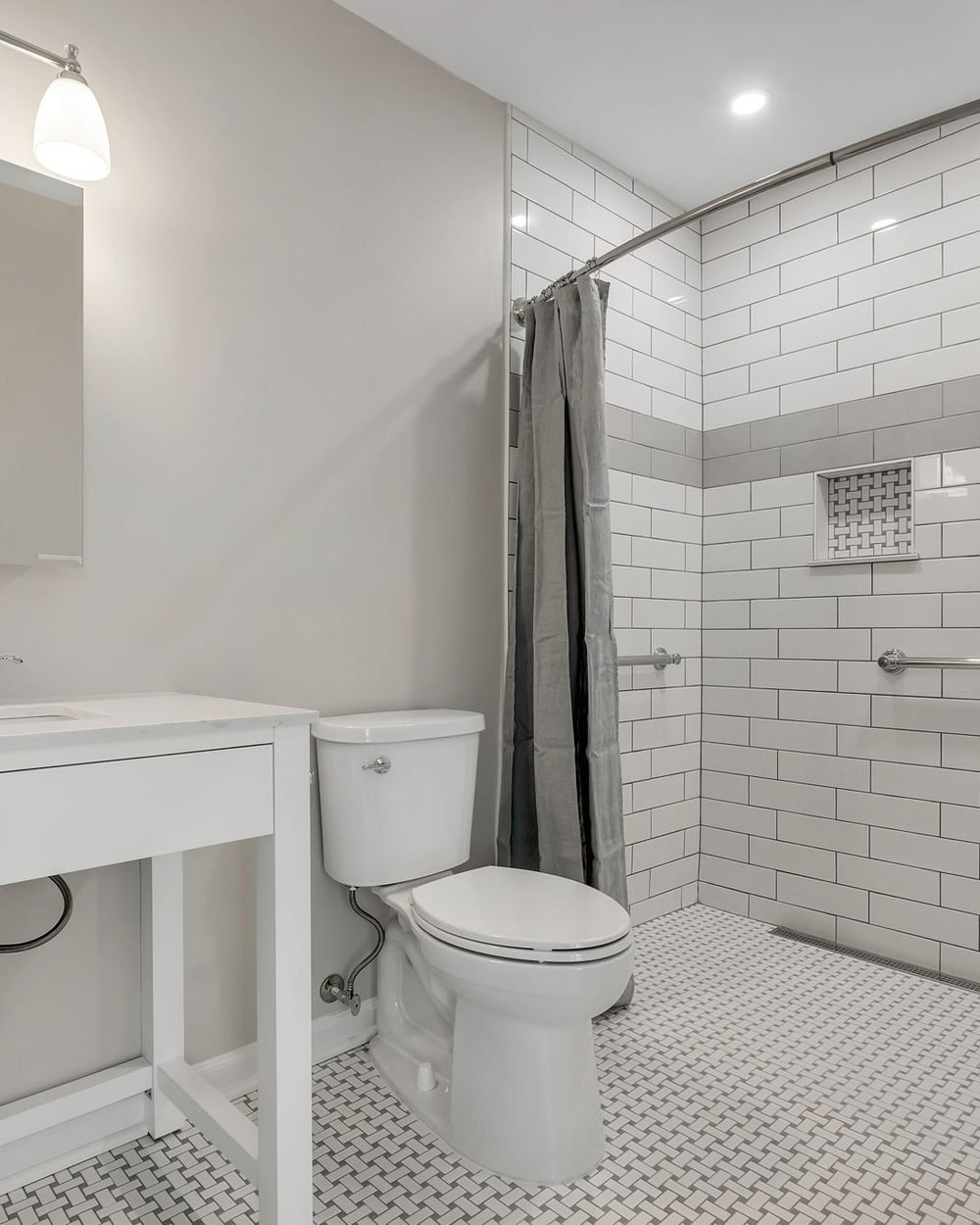 Curbless walk-in shower with white subway tile, integrated support rails and a basketweave mosaic floor. Tallahassee, FL