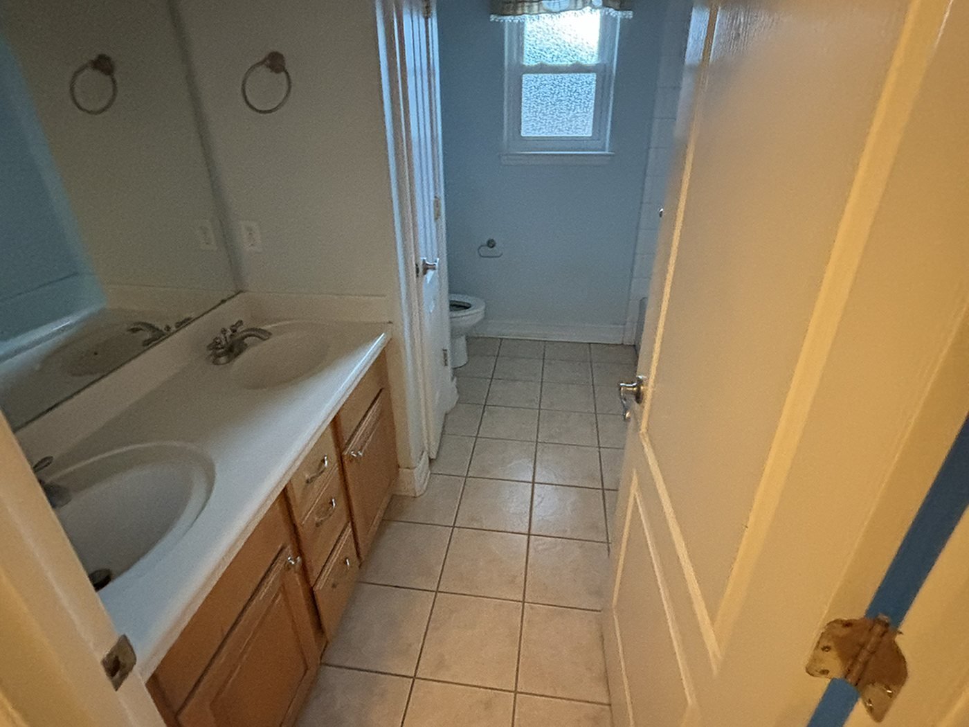 The original primary bathroom before renovation, with an oak vanity, a built-in tub surround and dated tile