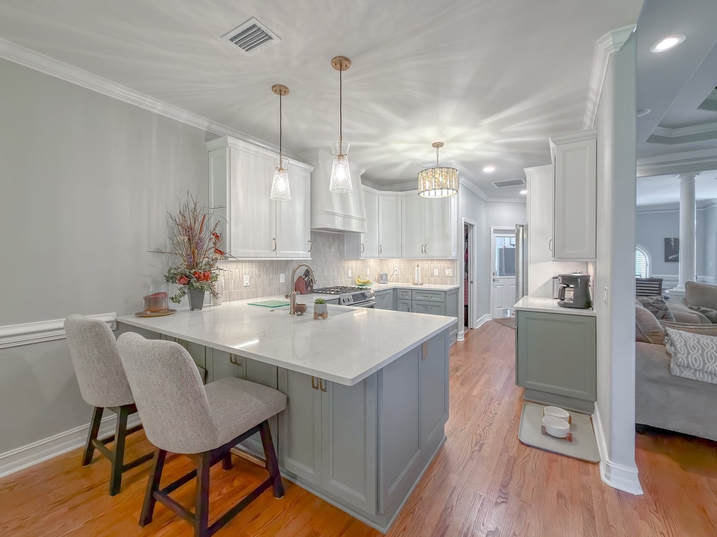 The same kitchen after renovation, with soft sage inset cabinetry, quartz countertops and brass fittings