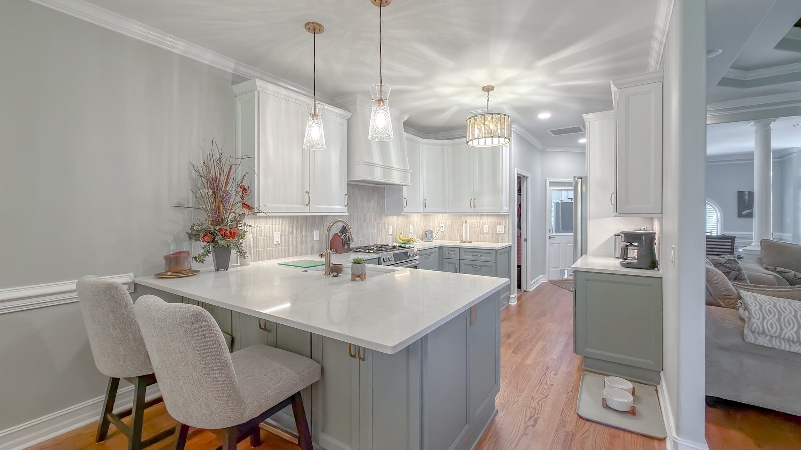 Renovated kitchen with a soft sage island, brass fittings and pendant lighting. Video still from a whole home renovation walkthrough in Tallahassee, FL