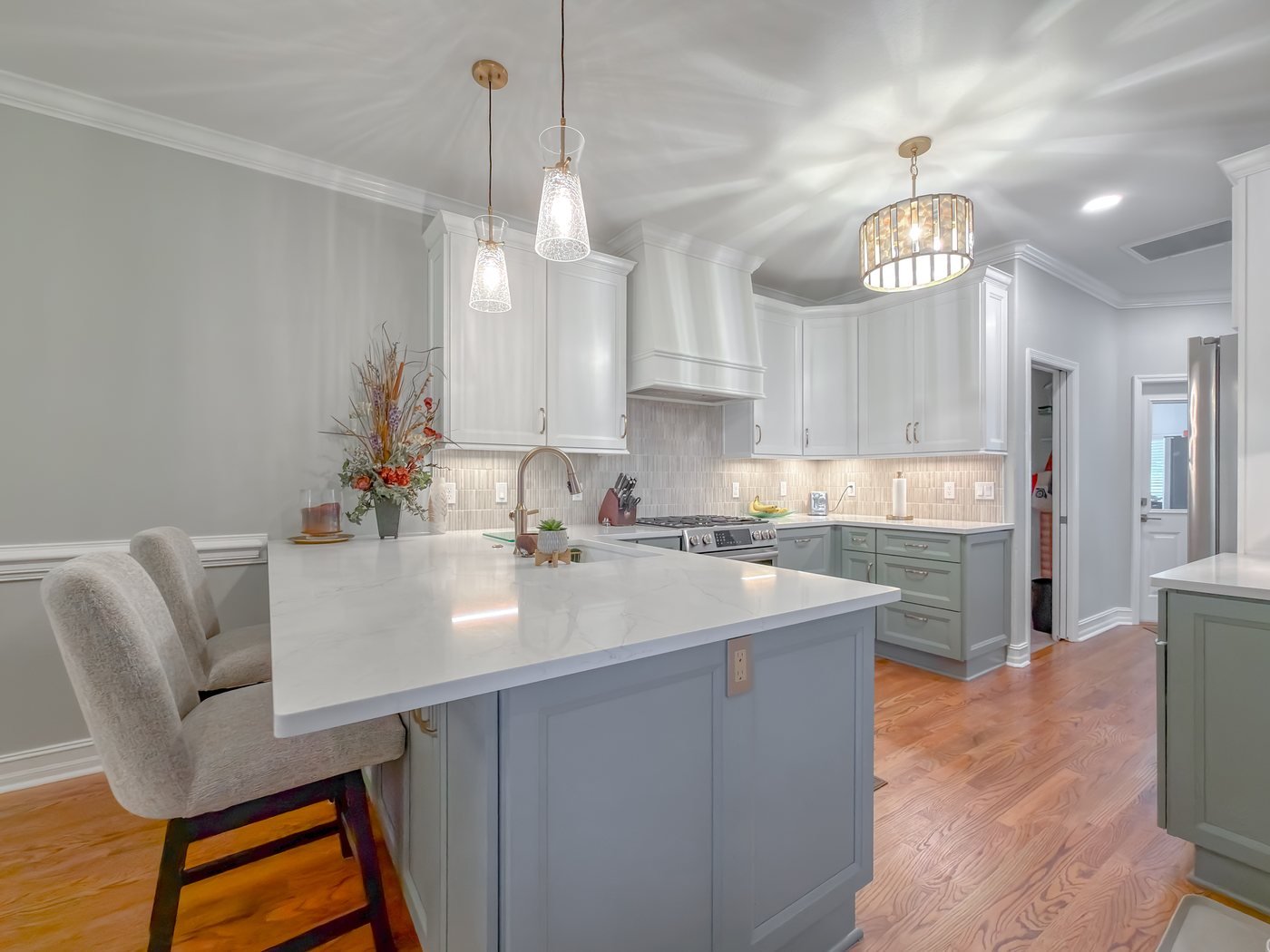 The same space after renovation, with sage inset cabinetry and quartz counters