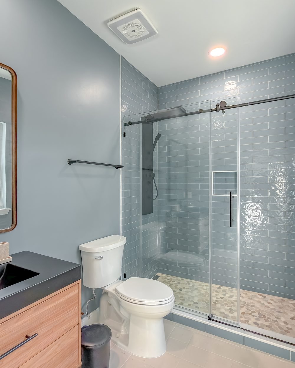 Guest bathroom with an oak vanity, black basin and glass shower enclosure. Bathroom renovation in Tallahassee, FL