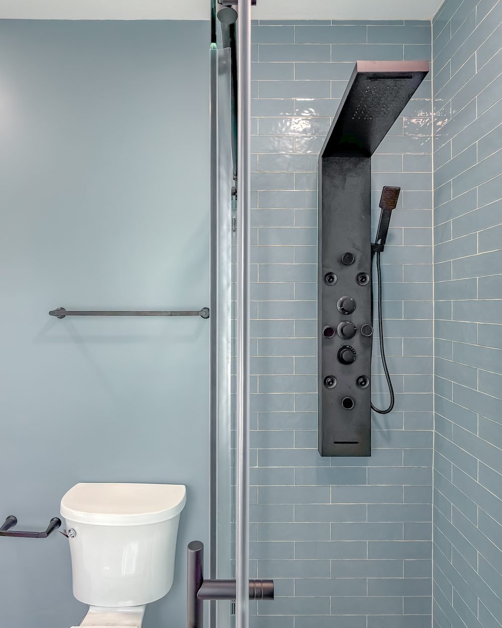 Walk-in shower with pale blue subway tile and a black shower panel. Bathroom remodeling Tallahassee, FL.