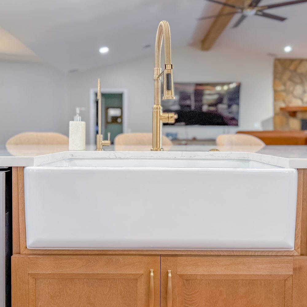 Farmhouse apron sink set into a wood island with a brass faucet