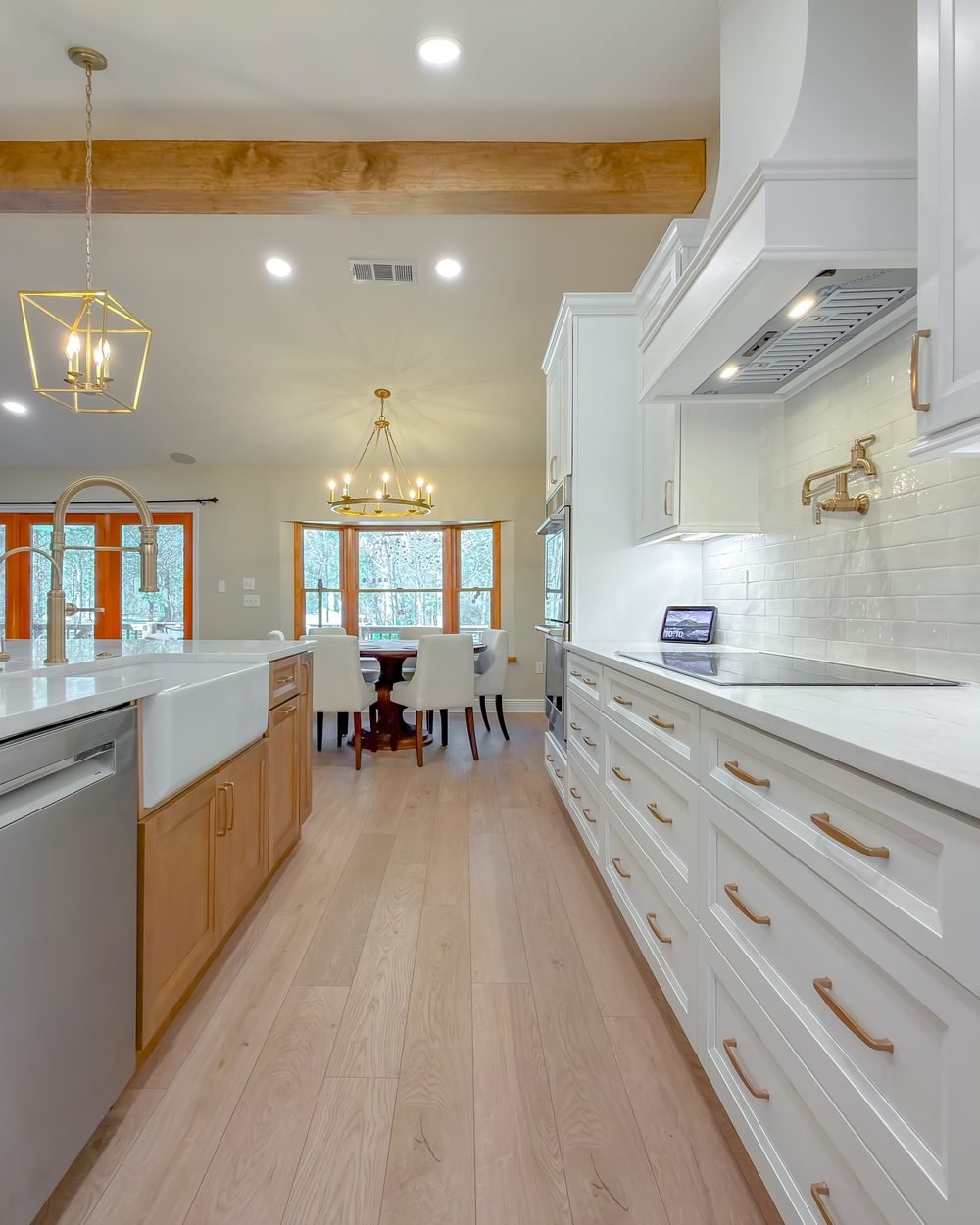 Open kitchen with a white range hood, exposed beam and brass pendant lighting in Tallahassee, FL