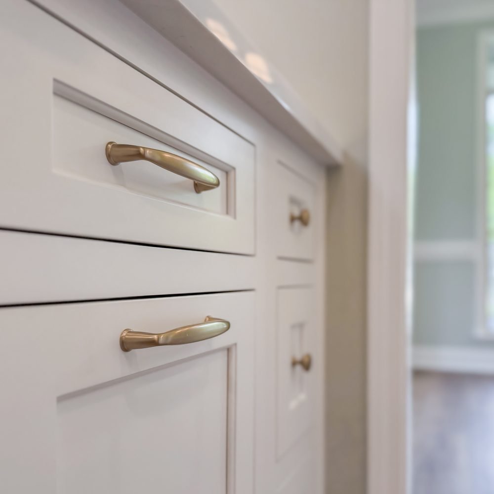 Detail of a painted drawer front with a brass pull on custom millwork