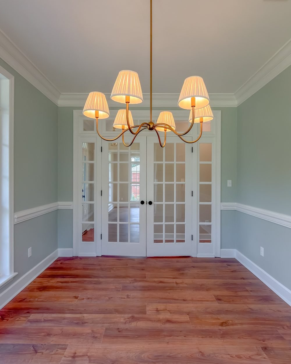 Formal dining room with wainscoting, a brass chandelier and a wall of windows. Tallahassee, FL