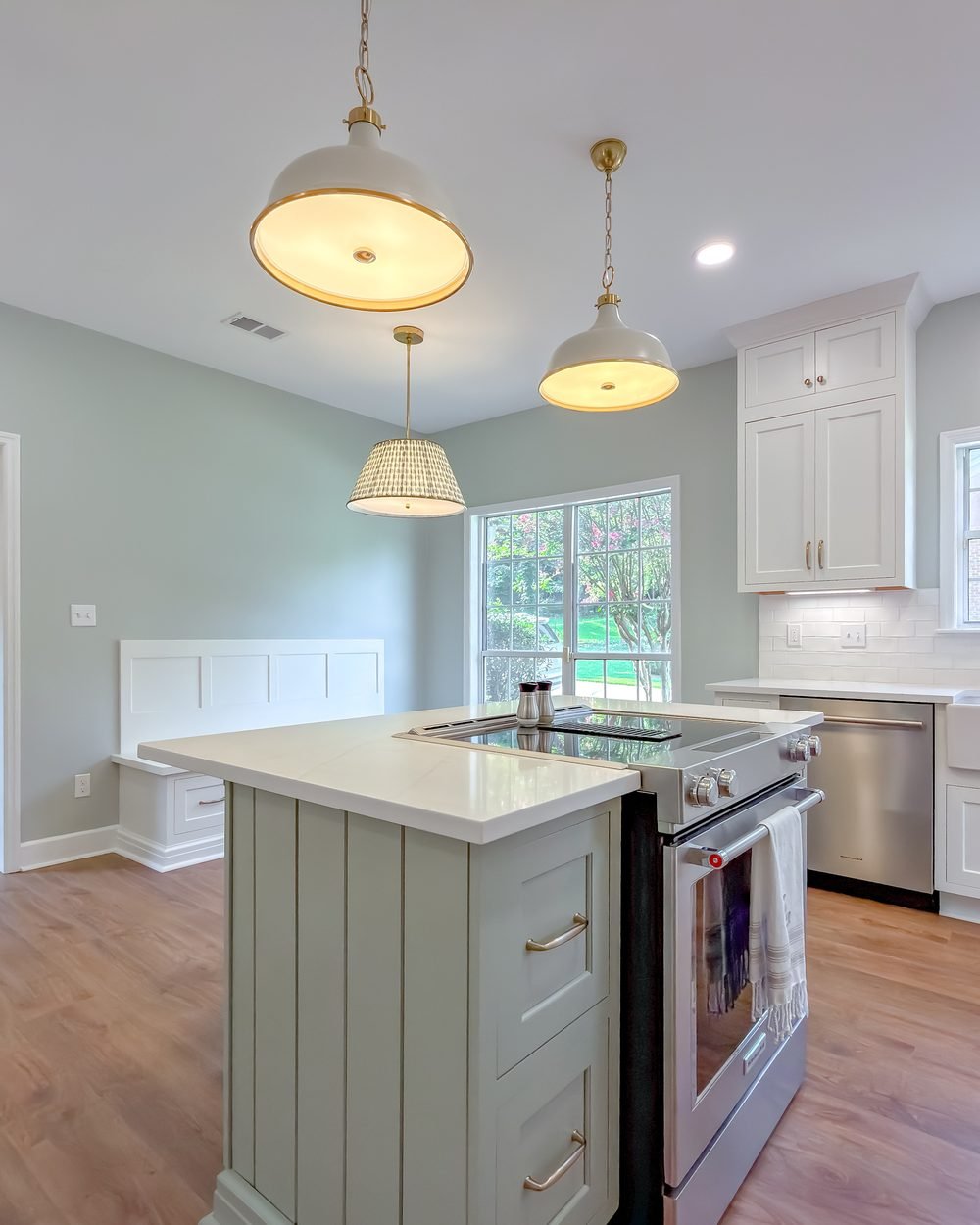 Kitchen with a soft green island, white cabinetry and pendant lighting in Tallahassee, FL