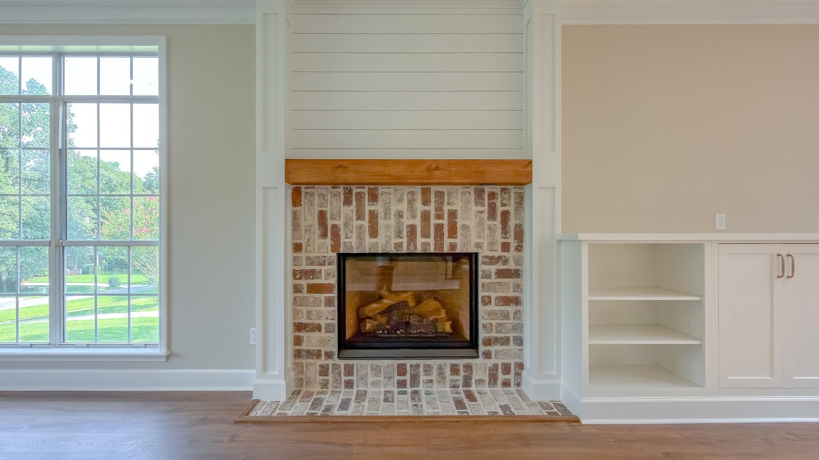 Living room with a brick fireplace flanked by custom white built-in cabinetry and shelving. Interior renovation in Tallahassee, FL