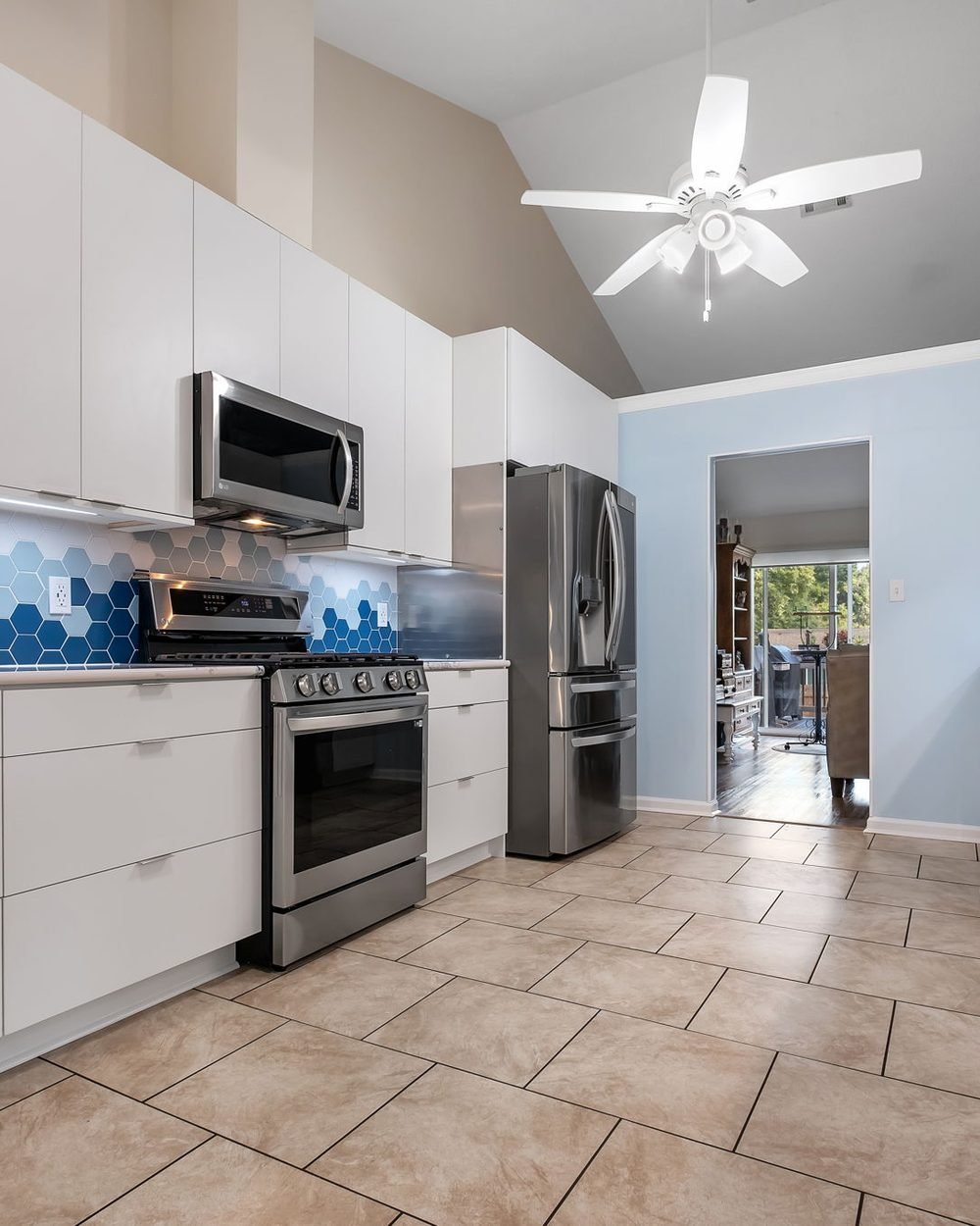 Galley kitchen with flat-panel white cabinetry, a blue and white hexagonal tile backsplash and a vaulted ceiling. Tallahassee, FL
