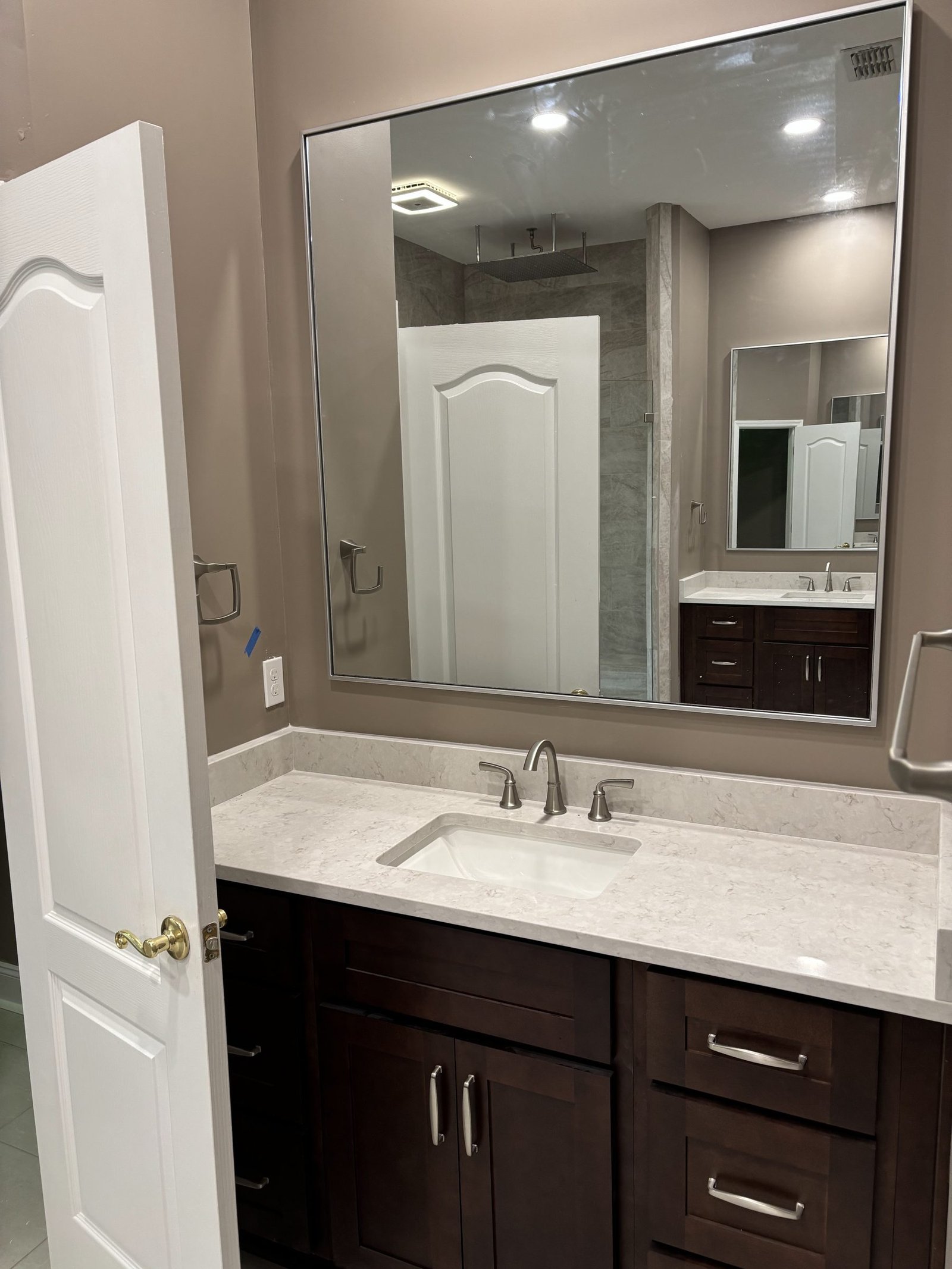 Bathroom vanity in dark shaker cabinetry beneath a wide framed mirror. Tallahassee, Florida.
