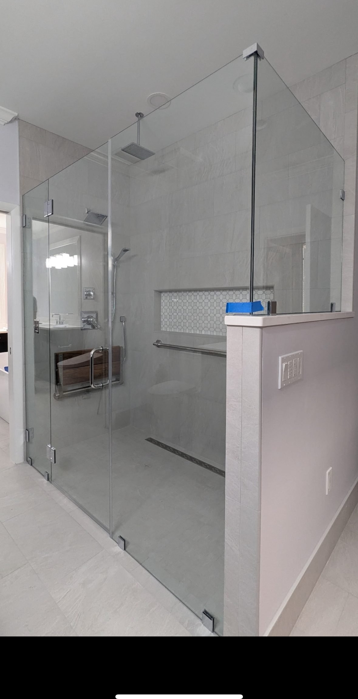 Frameless glass shower enclosure beside a tiled half wall. Tallahassee, Florida.