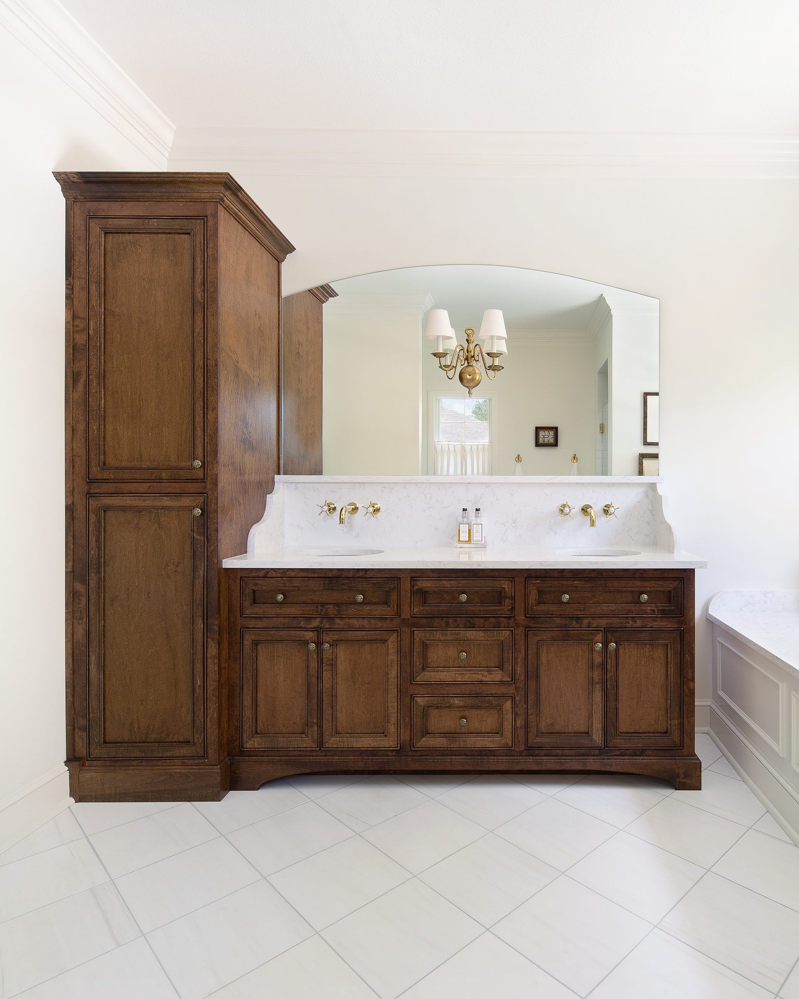 Traditional bathroom with a double vanity and a tall linen cabinet in stained wood. Tallahassee, Florida.
