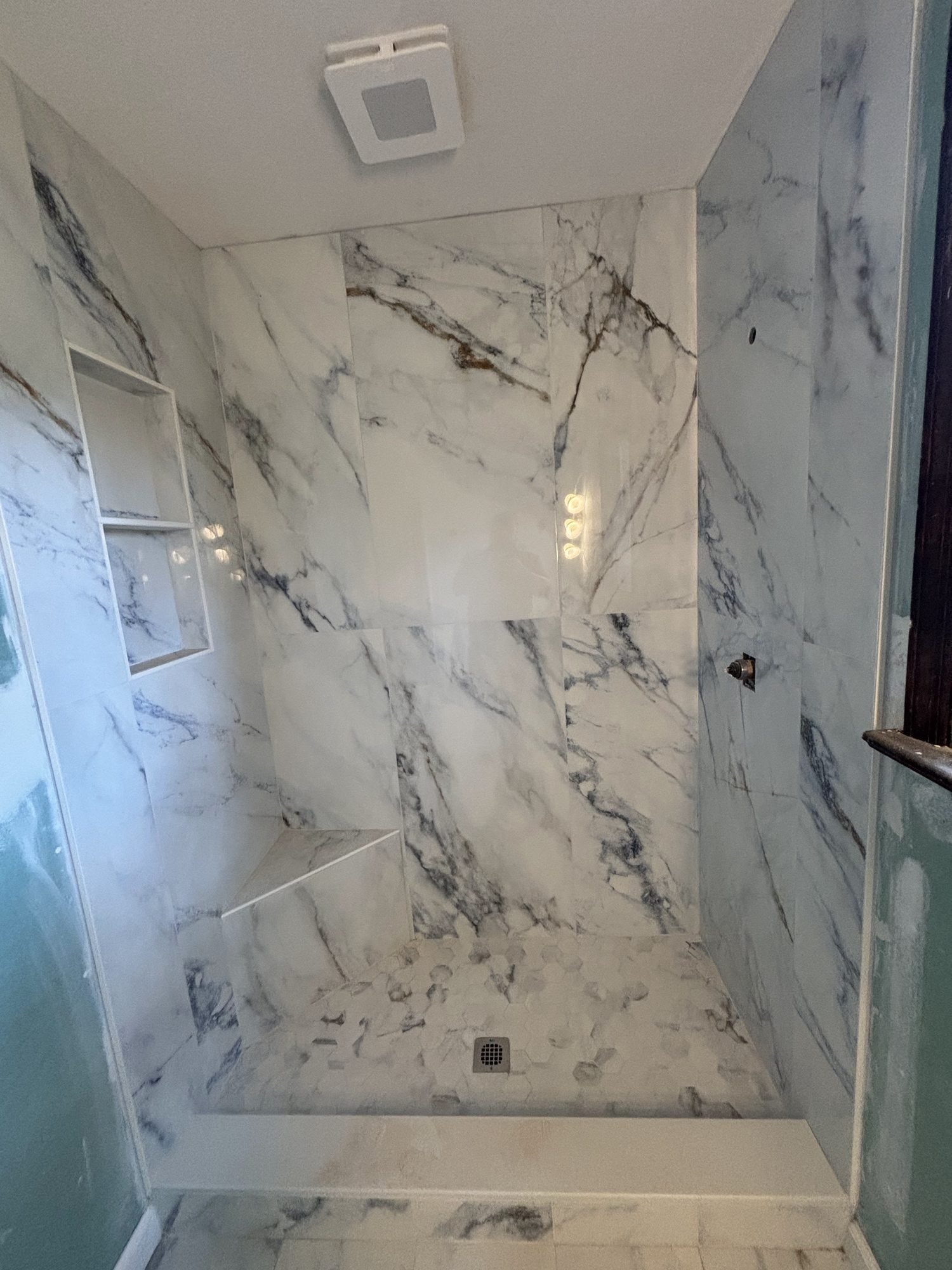 Detail of book-matched marble-veined slab shower walls with a recessed niche, Tallahassee, FL