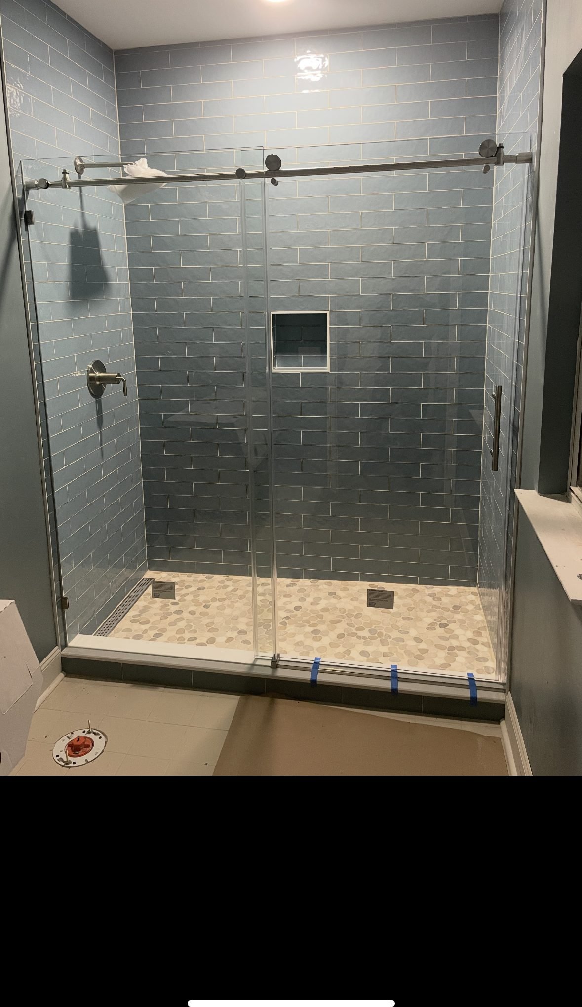 Shower in slate-toned subway tile with a sliding glass door and a pebble floor. Tallahassee, Florida.