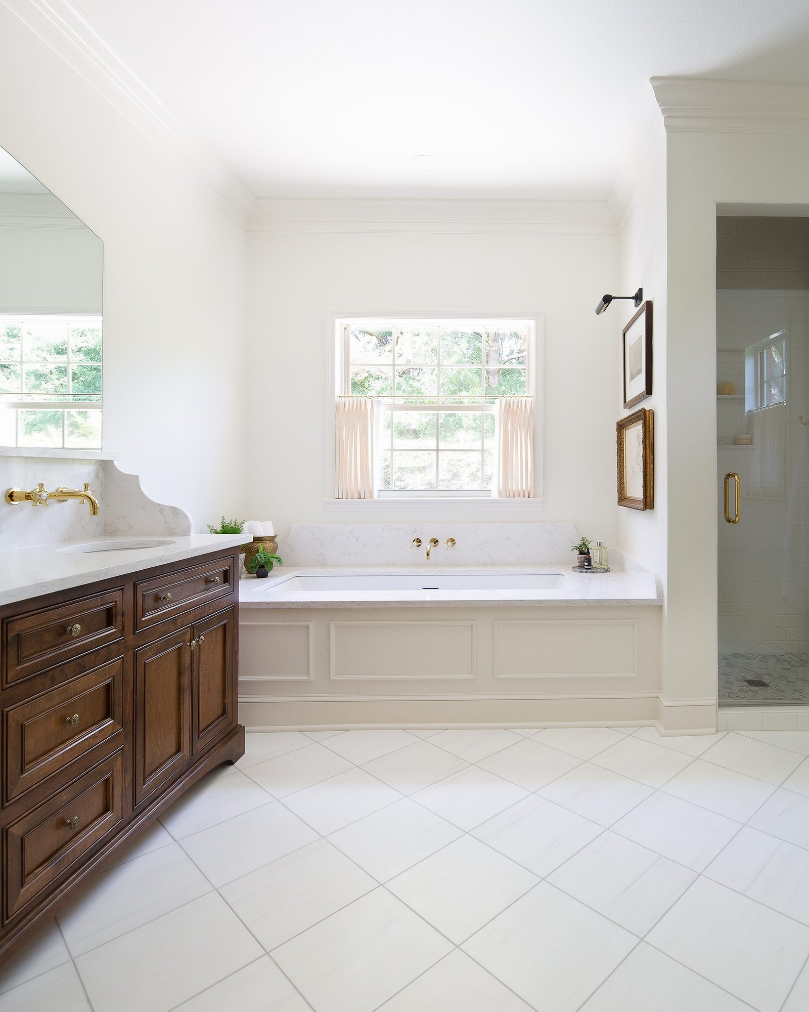 Primary bathroom with a stained wood vanity and a soaking tub set beneath a window. Tallahassee, Florida.