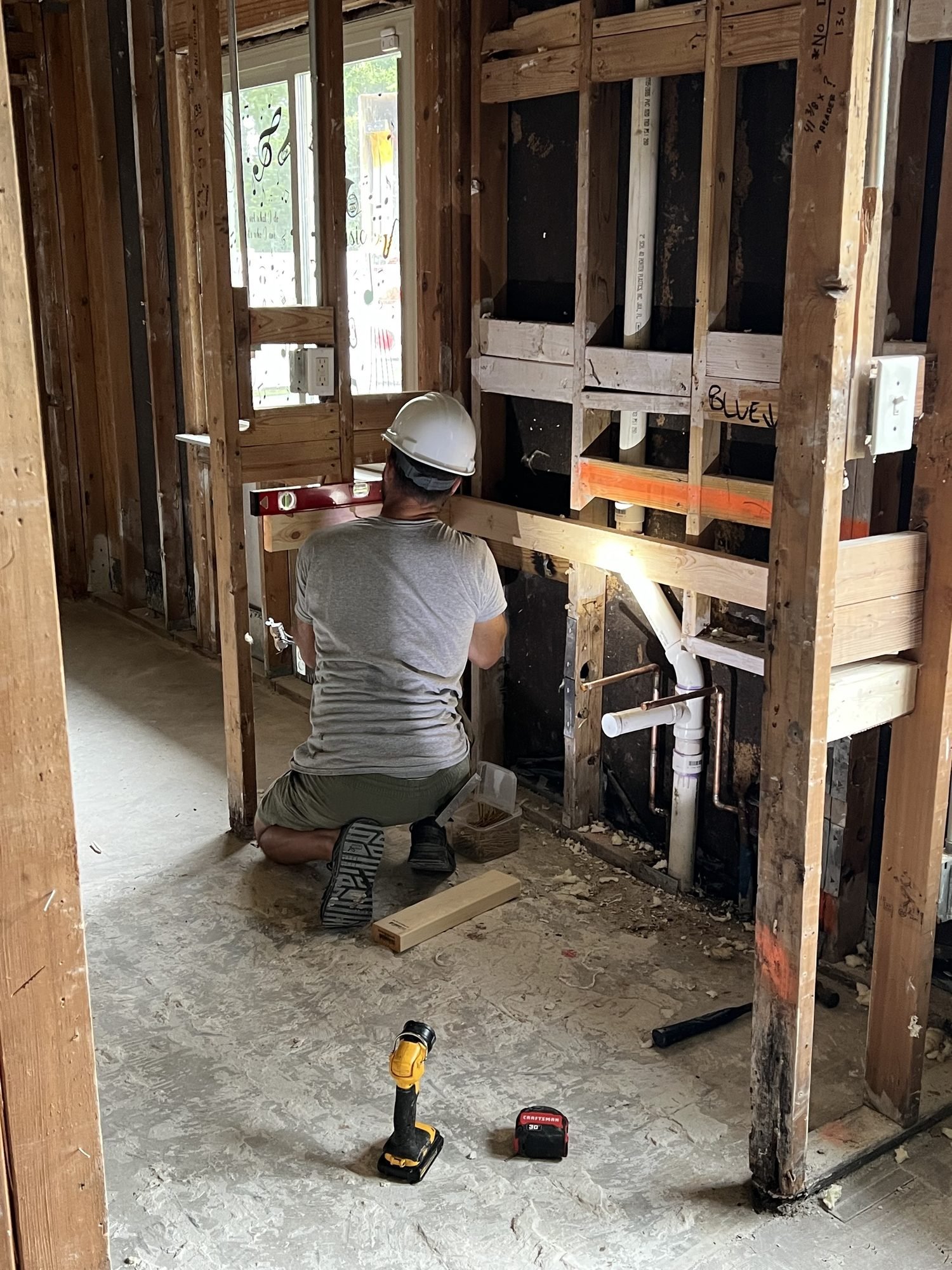 A Pristine Renovations carpenter drilling into a temporary shored opening while an engineered beam is installed, Tallahassee, FL