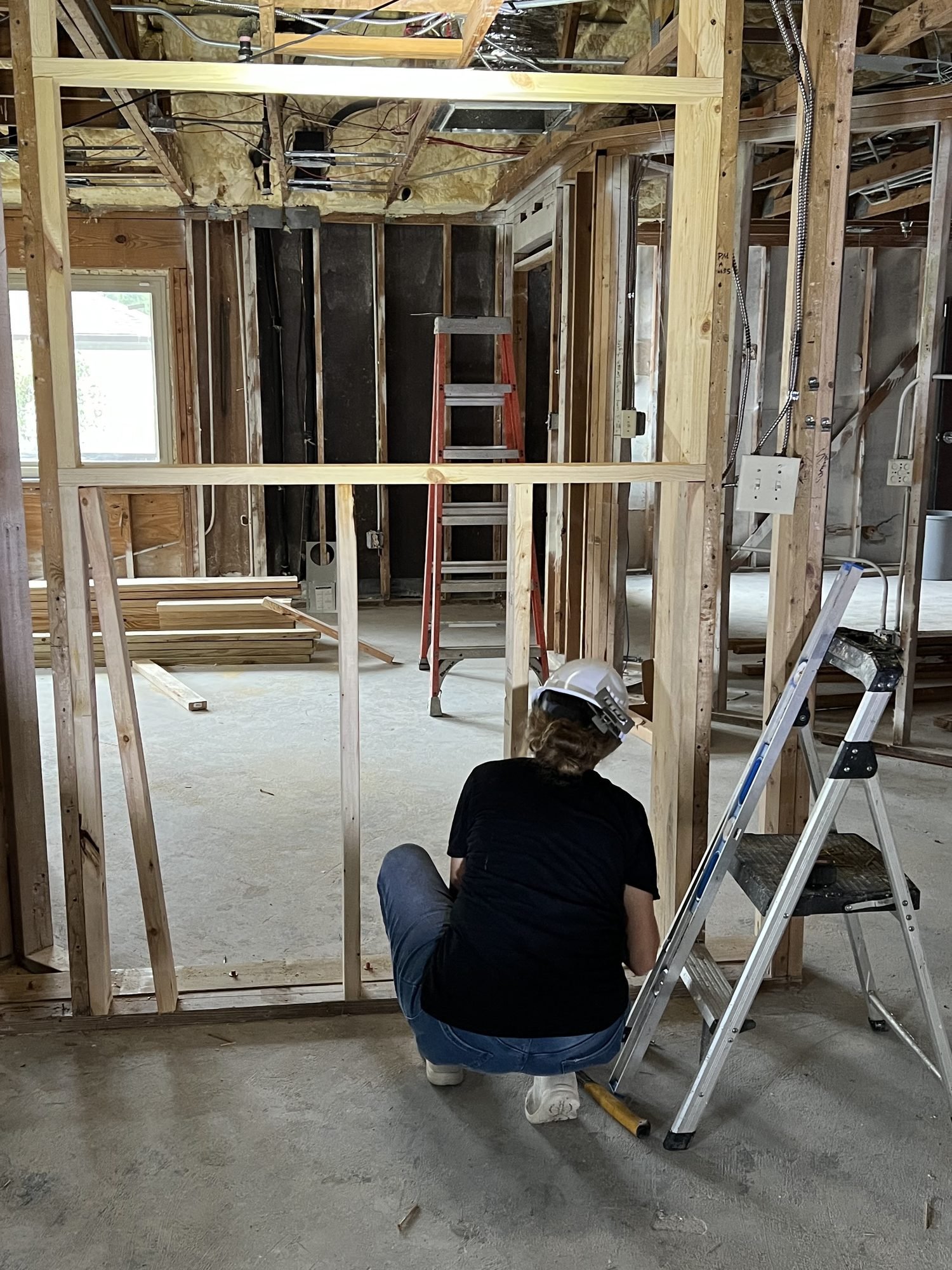 A Pristine Renovations crew member working from a ladder inside a newly framed opening during a whole home renovation in Tallahassee, FL