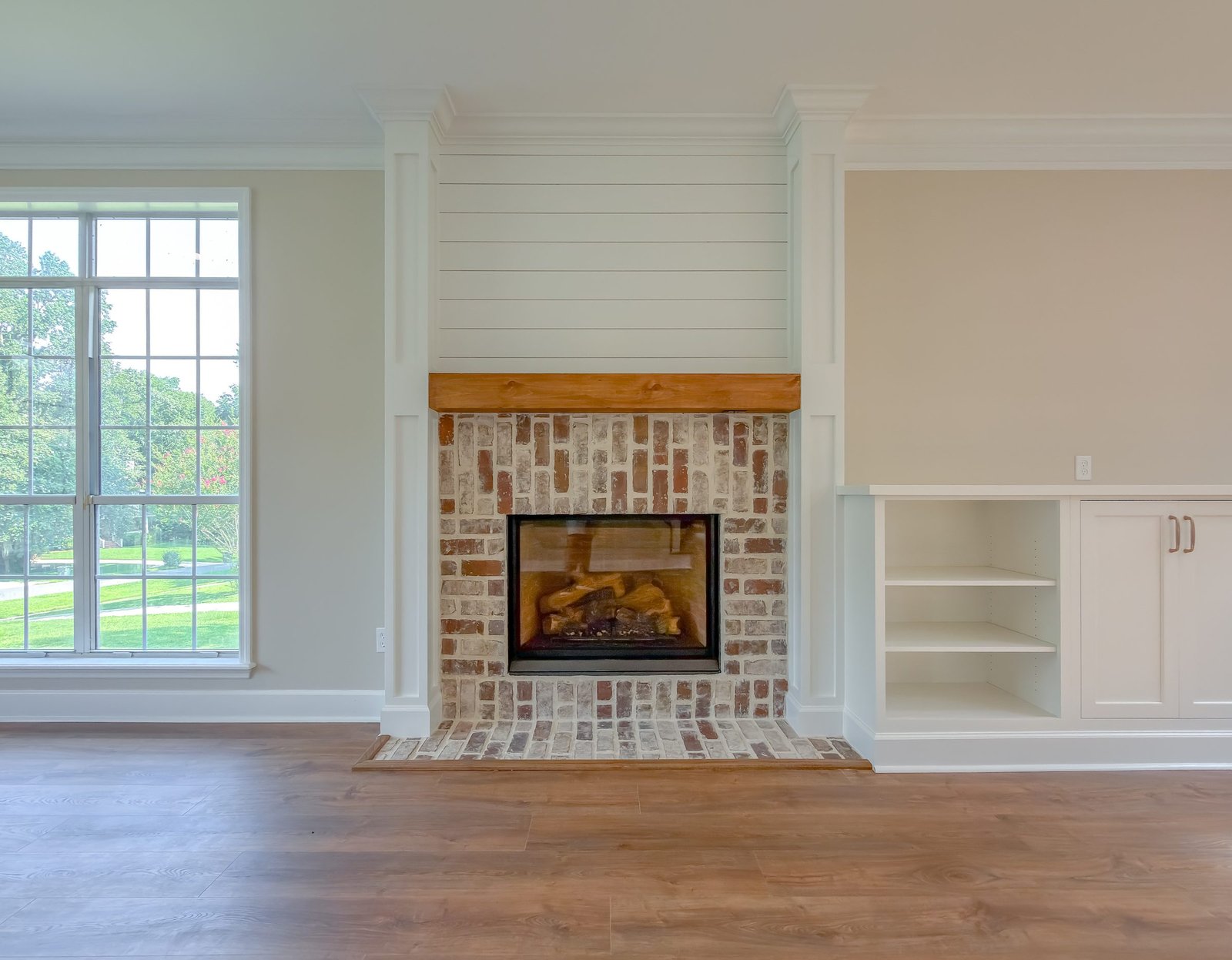 A brick fireplace with a shiplap chimney breast flanked by built-in cabinetry in a renovated living room, Tallahassee, FL