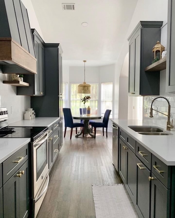 Deep green kitchen cabinetry with brass hardware opening to a dining area. Tallahassee, Florida.