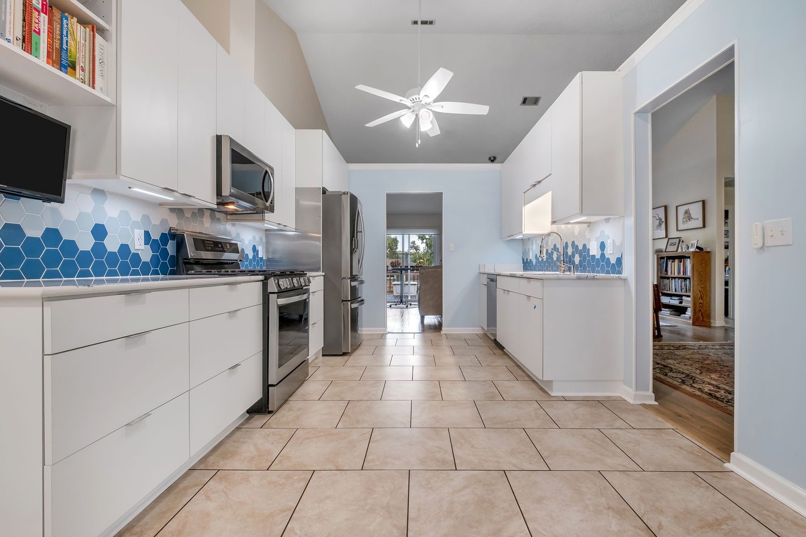 Galley kitchen with white cabinetry and a blue hexagonal tile backsplash. Tallahassee, Florida.