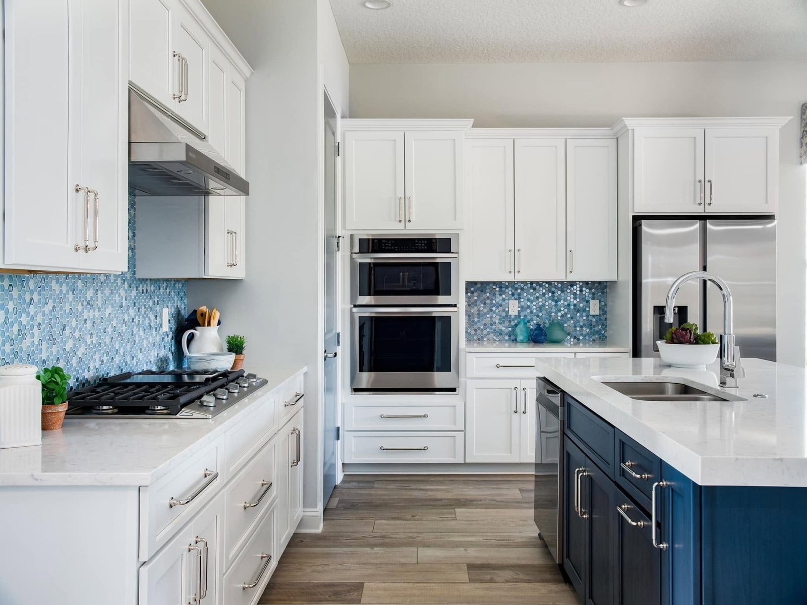 Renovated kitchen with a navy island, white perimeter cabinetry and a blue mosaic tile backsplash. Tallahassee, Florida.