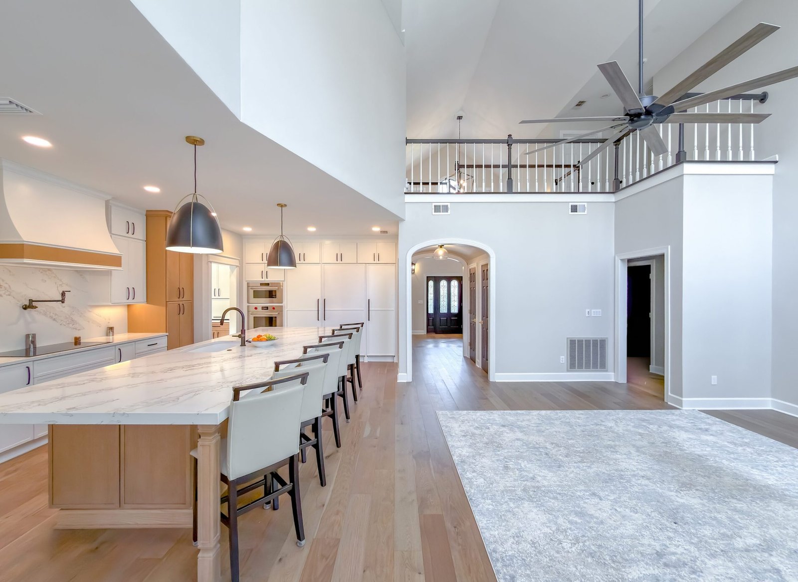Open plan kitchen and great room with a vaulted beamed ceiling, a long island with bar seating and wood flooring throughout, Tallahassee, FL