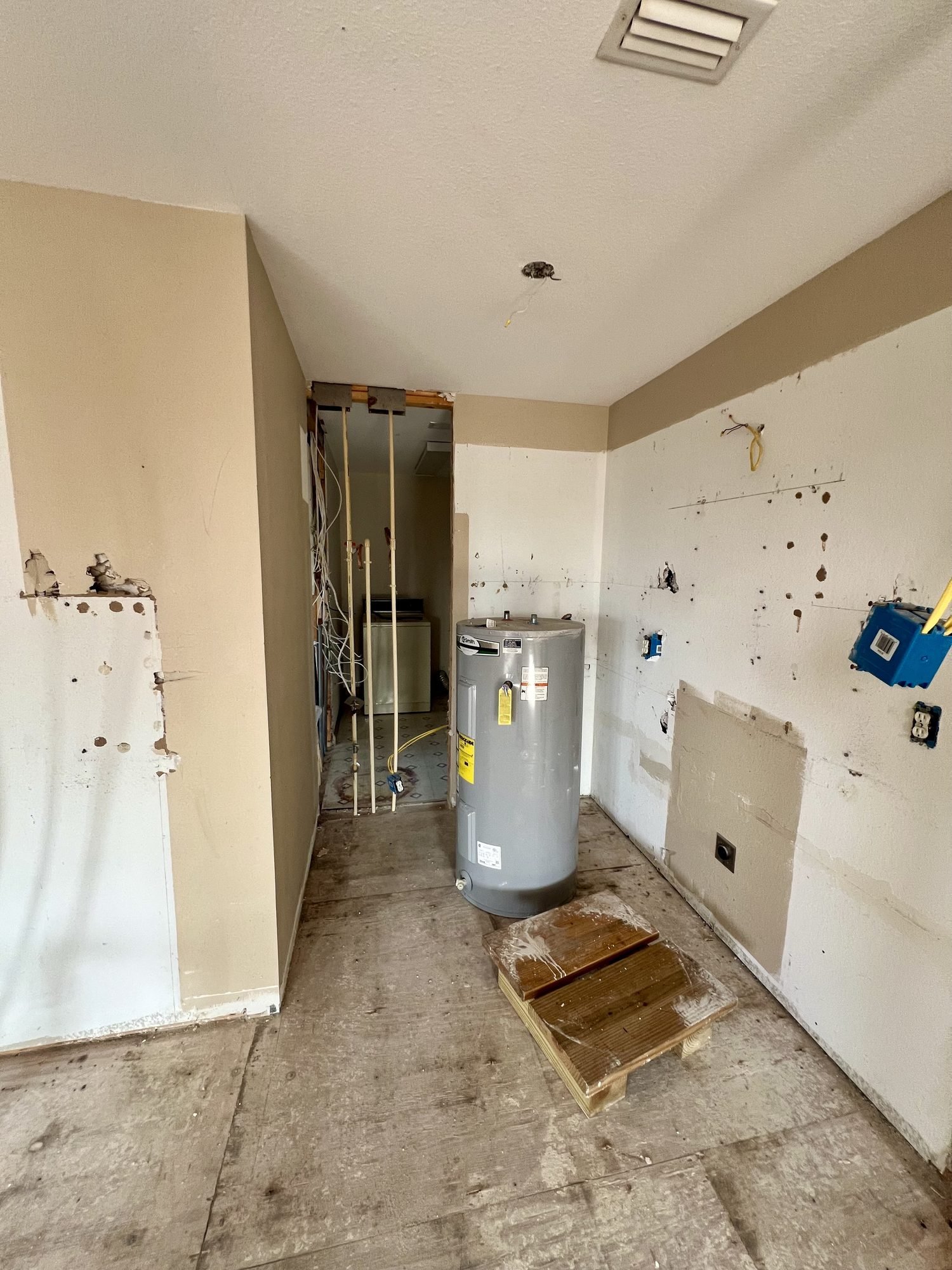 A gutted utility area with plumbing stub-outs and a new water heater during a whole home renovation, Tallahassee, FL