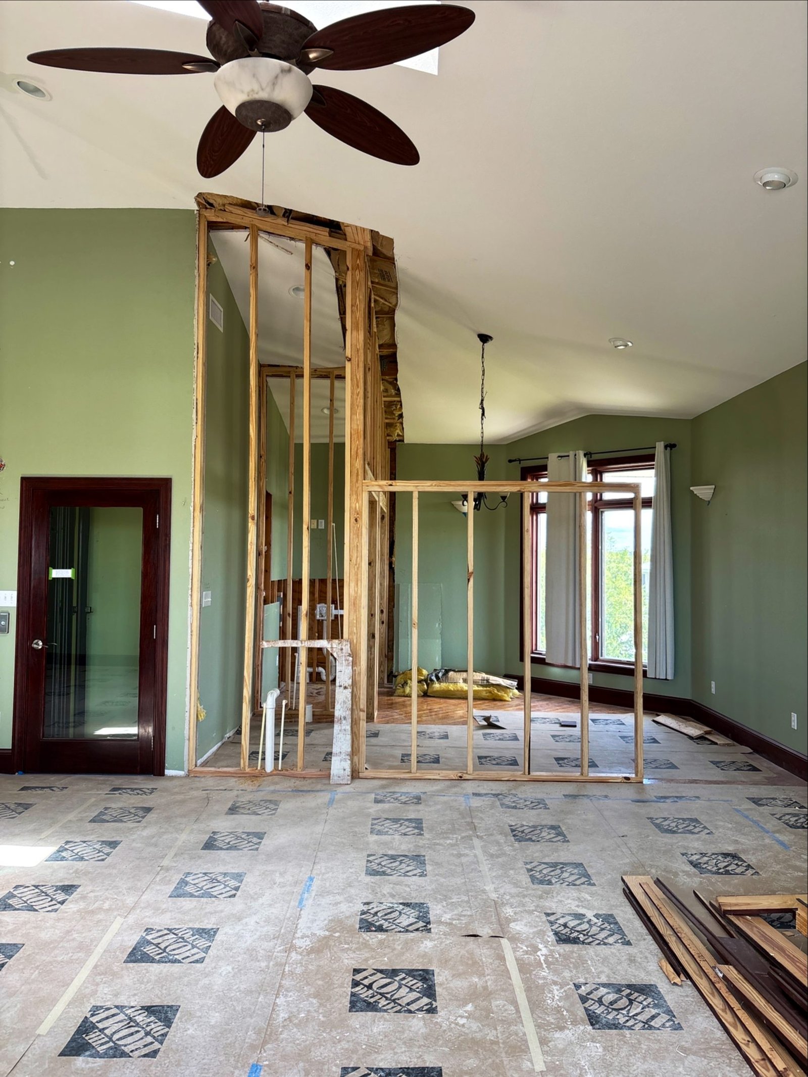 A load-bearing wall opened between two rooms during demolition, with original flooring being removed, Tallahassee, FL