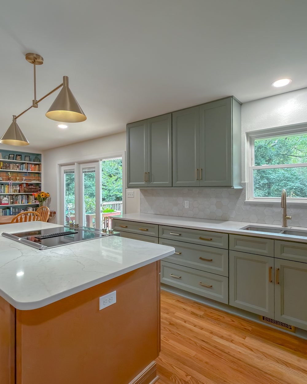 Sage green kitchen with a wood island, quartz counters and brass cone pendants. Kitchen renovation in Tallahassee, FL