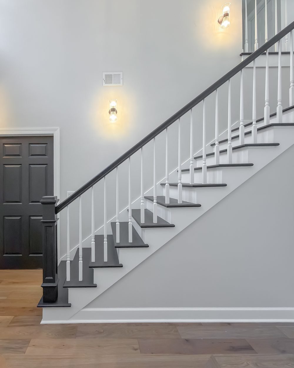 Entry hallway with a dark door, herringbone wood flooring and a staircase beyond. Tallahassee, FL