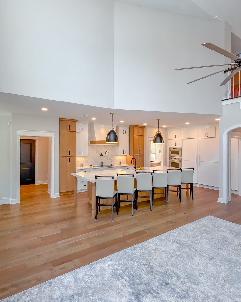 Double-height great room opening to a renovated kitchen with a long island and bar seating. Whole home renovation in Tallahassee, FL