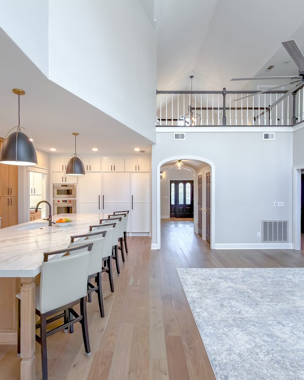 Kitchen with white upper cabinets, natural white oak base cabinets, a long quartz island and matte black hardware. Tallahassee, FL