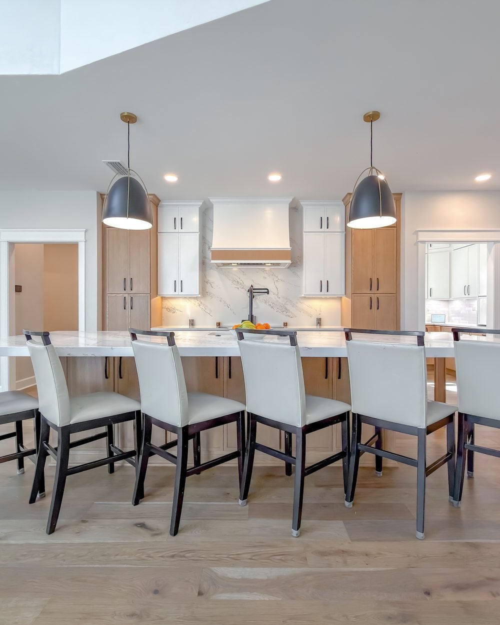 Kitchen with white uppers, white oak base cabinets and a long quartz island with bar seating. Tallahassee, FL