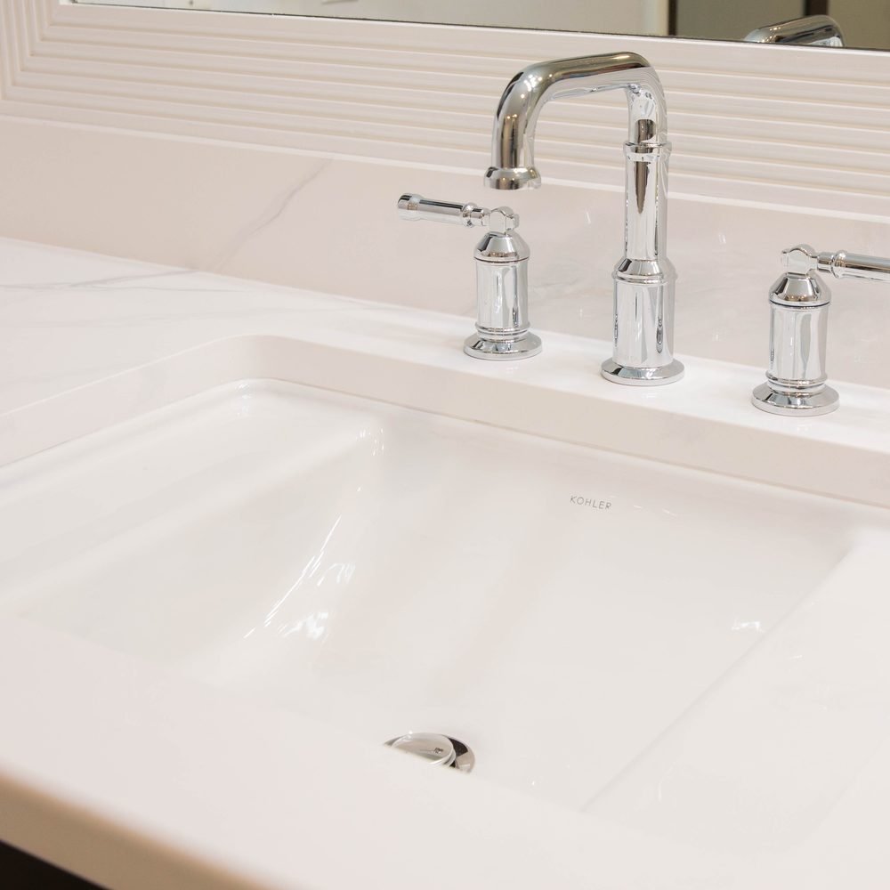 Detail of an undermount basin with a polished chrome widespread faucet on a marble-veined quartz vanity top. Tallahassee, FL