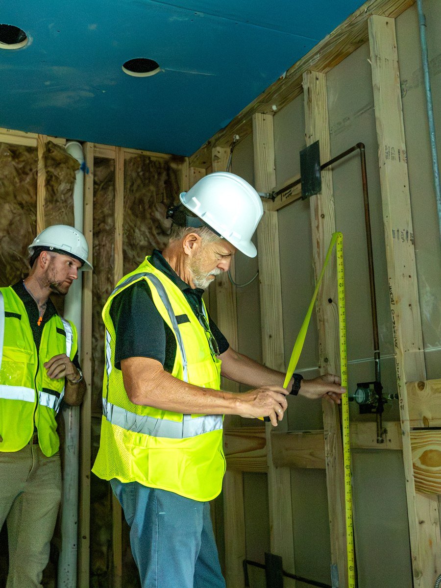Two Pristine crew members inspecting exposed wall framing