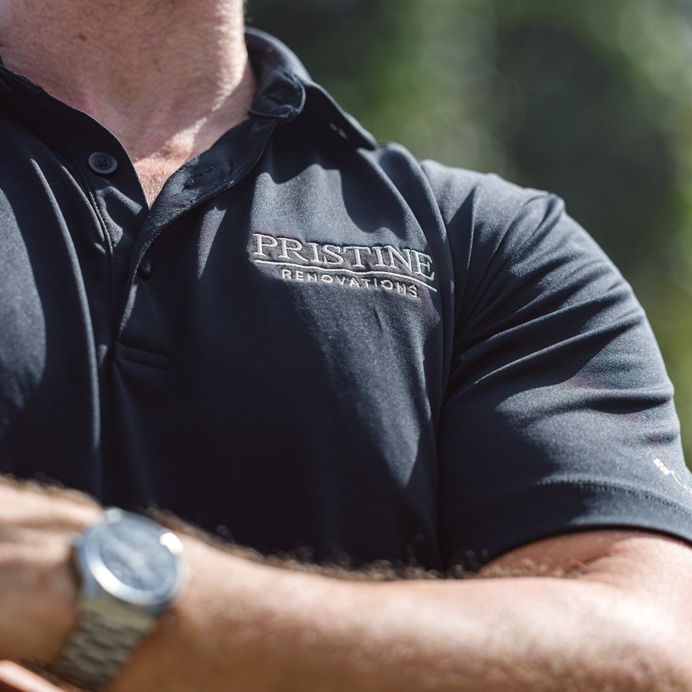 Embroidered Pristine Renovations logo on a team member’s work shirt