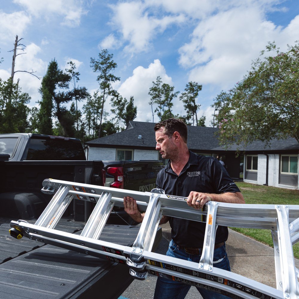 Pristine crew member handling a ladder beside the company truck