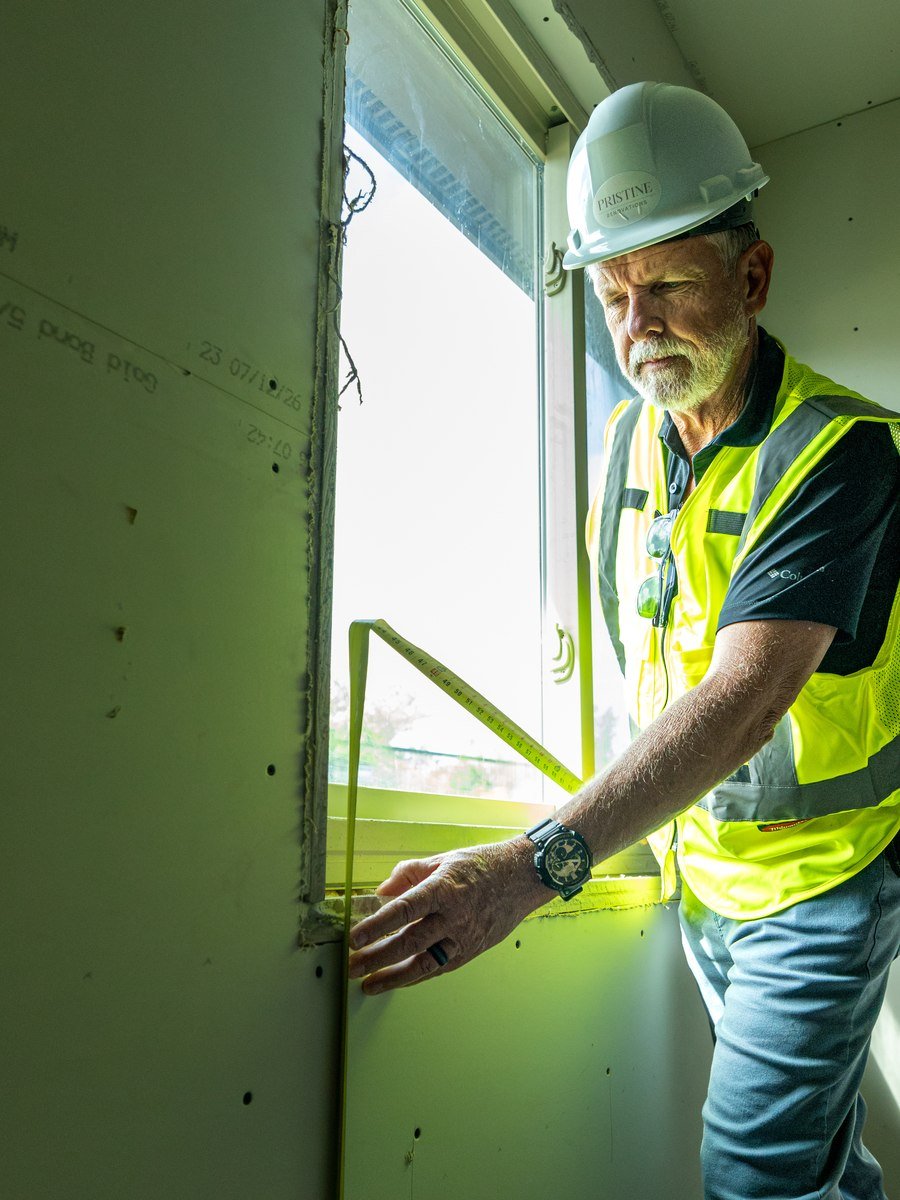 Pristine worker checking a window opening during interior construction